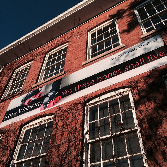 Looking up at the red brick wall of the Art Gallery Guelph, which has a banner for my solo exhibition on it: Kate Wilhelm, Yes these bones shall live, Jan. 22 to Mar. 29, 2015.